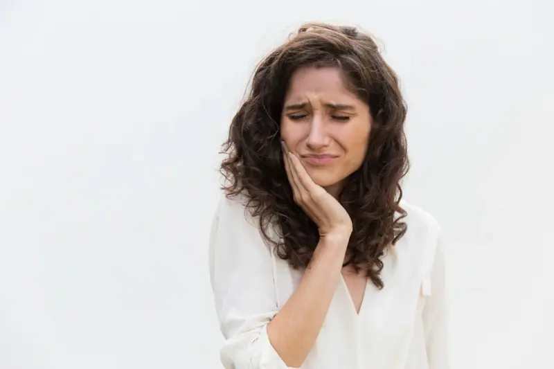 Patient holding her cheek from tooth pain before an emergency dental visit